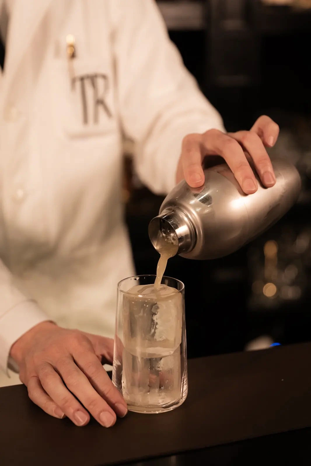 Hands pouring a cocktail from a shaker at TRENCH