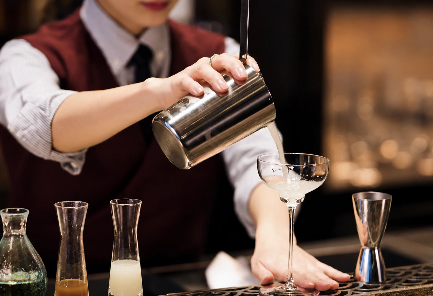 Pouring from a mixing tin into a cocktail glass
