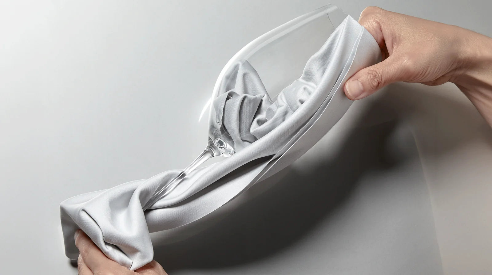 Hands polishing a glass with a white cloth